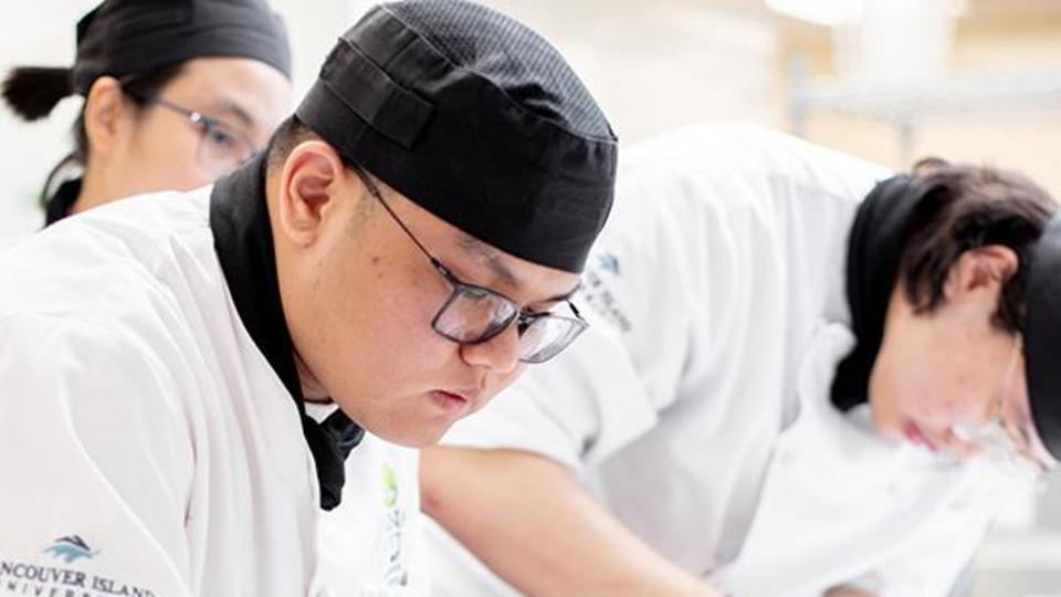 VIU Culinary student plating food in the kitchen