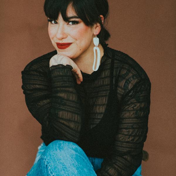 Riley Yesno sits, legs crossed, chin on hand